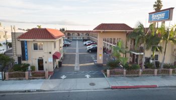 A motel with a parking lot, multiple parked cars, and a sign reading 