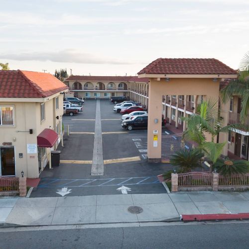 The image shows a motel parking area with cars and a sign reading 